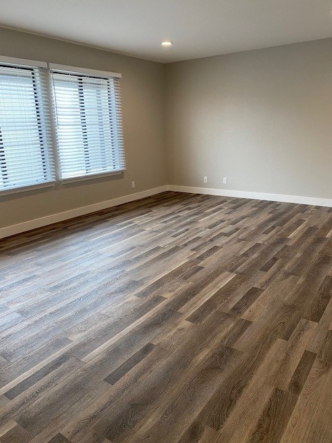 A room with wooden flooring and a window with blinds.